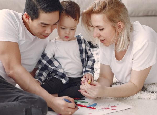 Loving family creating art together, fostering play and connection indoors.